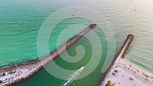 Sea shore inlet with white yachts sailing on colorful waves. North and South Jetty on Nokomis beach near Venice, Florida