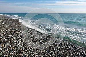 Sea shore with pebbles. wet sea pebbles on the beach and quiet sea surf