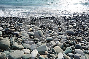 Sea shore with pebbles. wet sea pebbles on the beach and quiet sea surf