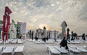 The sea side at sunset with umbrellas, sand and sun beds.