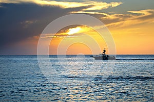 sea and speedboat over cloudy sky and sun during sunset in Cozumel, Mexico