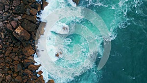 Sea splashing coastal stones aerial view. Ocean water breaking rocks seashore.