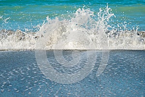 Sea splashing wave on the beach with sprays and foam. Beautiful natural background.