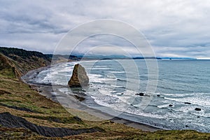 A sea stack dominates the beach on a foggy day at Cape Blanco State Park, Oregon, USA