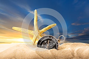 Sea star and compass in sand on sunset