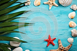 Sea stars, sea stones, palm leaves and shells lying on a blue wooden background . There is a place for labels.