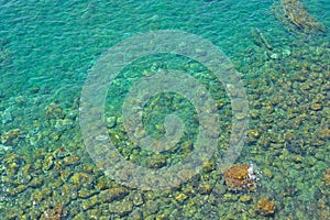 Sea stones in the sea water. Pebbles under water. The view from the top. Nautical background. Clean sea water. Transparent sea