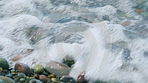 Sea Stones Are Visible Through Clear Water Of Waves. Pebbles On The Seashore.