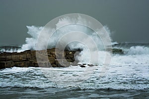 Sea storm waves crashing and splashing against jetty