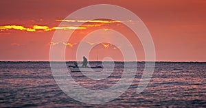 Sea sunrise and sailing fishing boat with fishermen over calm ripple water waves video