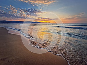 Sea sunrise scene, natural background. Early morning on the beach with a peaceful view to the dawn above the hills. Summer holiday