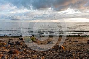 Sea at sunset with big round stones on the shore.