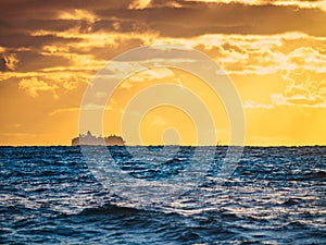Sea at sunset with cargo ship on horizon