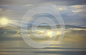 Sea, sunset and cloud on mountains in morning, reflection and island with landscape in nature. Blue sky, clouds or