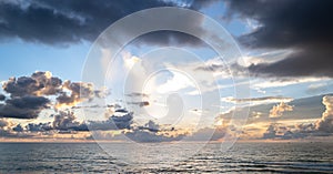 Sea sunset with cloudy sky and sun through the clouds over. Clouds Ocean and sky background, seascape.