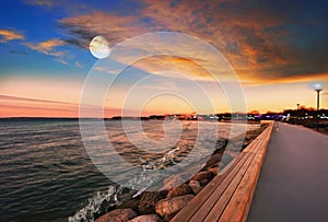 Sea sunset colorful evening sky and moon on cloudy  skyline,  light reflection on seawater, gold summer city  in   Tallinn old tow
