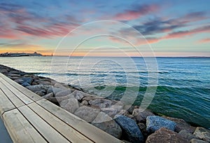 Sea sunset colorful sky ,skyline,  light reflection on seawater, seafront promenade and stones on beach,blue sky and pink fluffy c