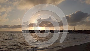 Sea sunset with light reflections and the silhouette of the people on the pier