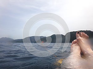 Sea surface with buoys, woman legs under water and mountains in the distance. View and shooting from water