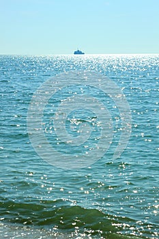 Sea travel. Beautiful view of the waves on a bright sunny day. Sun glare on the water. Ships sail away on the horizon