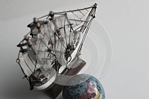 Sea Travel Concept Image. Globe And Wooden Model Of Old Ship In Muted Colors Style