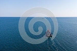 The sea tug moves from the port water area towards the open sea. Photo from the helicopter. View from above