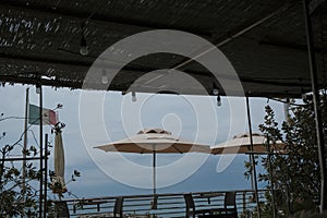 sea view across the open-air cafe on the beach and sun umbrellas, and the Italian flag. Ligurian sea, Sestre Levante, Liguria