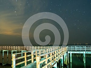 Sea view near mangrove forest with man made wooden barrier for wave protection, under starry nigh cloudy sky