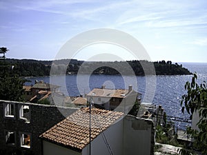 The sea is visible behind the roofs of houses of different storeys in the seaside town photo