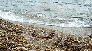 Sea water on a beach with thick sand, small waves next to a rock