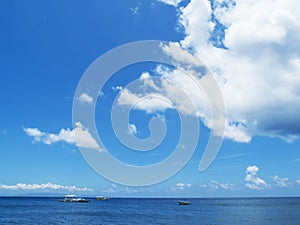 Sea water landscape with blue sky and ripples. Seashore view with white boats.