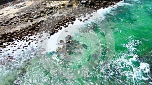 The sea water\'s wave splashing over to a shoreline repeatedly