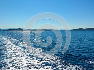 Sea water ship trail with white foamy wave. Tropical islands ferry travel. Bubble tail after cruise ship. Deep ocean view.