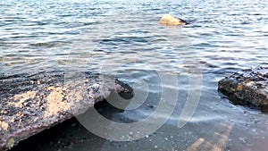 Sea water with a small ripple of waves and the water smashes on the stone. Seascape.