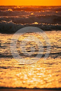 Sea water surface at sunset. Natural sunset warm colors of ocean. Sea ocean water surface with foaming small waves at