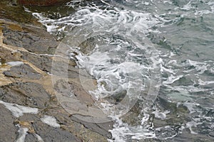 Sea water tide hitting against a man made rock barrier