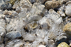 Sea water and wave bubbles over rocks
