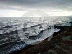 Sea wave against the background of thick clouds and the breaking sun