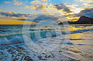 Sea wave on the beach, the surf on the Black sea coast at sunset.