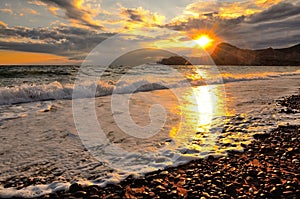 Sea wave on the beach, the surf on the Black sea coast at sunset.