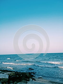 Sea wave with Blue sea and clearly sky. Evening light. Rock beach.