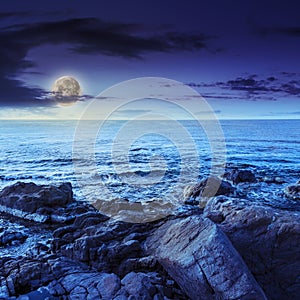 Sea wave breaks about boulders at night