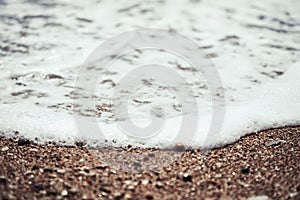 Sea wave foam on beach sand close up