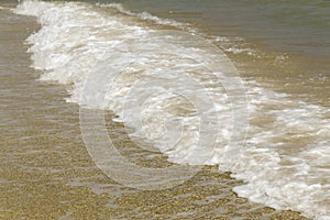 Sea wave with foam ran to the beach