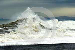 Sea wave with foam and spray during a storm. The concept of tension and struggle.