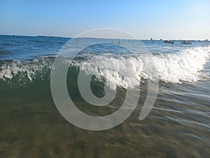 Sea wave with foam and sun glare