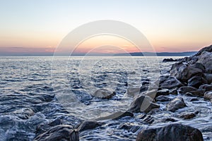 The sea wave hits the stones at sunset near the coast of the Holy Mount Athos