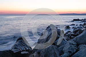 The sea wave hits the stones at sunset near the coast of the Holy Mount Athos