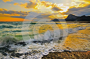 Sea wave on rocky sea coast at sunset