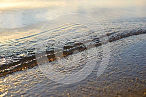 Sea wave and sand seashore. Golden sun light over the sea ocean waves.